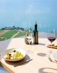 une table avec une assiette de nourriture et deux verres de vin dans l'établissement Baron Tavernier Hotel Restaurant & SPA, à Chexbres