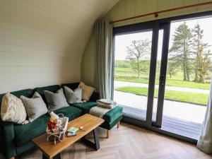 a living room with a green couch and a table at Willow in Llanidloes
