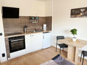 a kitchen with white cabinets and a table with a sink at Low Budget Apartment Cologne in Cologne