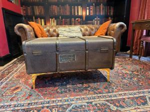 a leather couch with an old trunk on a rug at Absolute Clapham in London