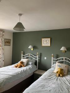 two beds in a bedroom with two teddy bears on them at Brandreth Barn in Burscough