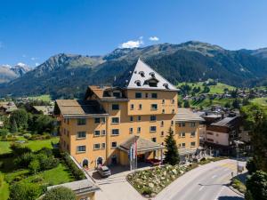 un grand bâtiment jaune avec une tour sur une montagne dans l'établissement Hotel Vereina, à Klosters
