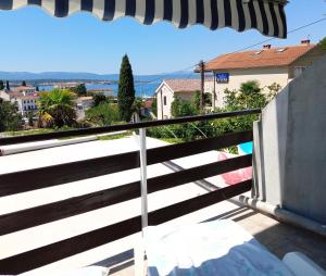 a balcony with an umbrella and a view of a city at Guesthouse Cecilia in Malinska