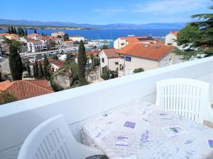 a balcony with a table and chairs and a view of the city at Guesthouse Cecilia in Malinska