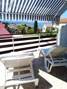 a white chair and a chair sitting on a patio at Guesthouse Cecilia in Malinska