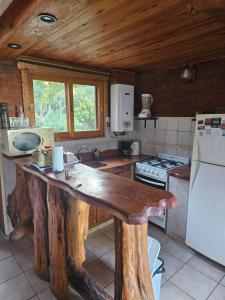 a kitchen with a wooden table and a refrigerator at Cabañas Huinca Mapu - Sierra de los Padres in Sierra de los Padres