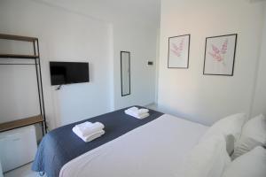 ein weißes Schlafzimmer mit einem Bett und zwei gefalteten Handtüchern in der Unterkunft Hotel Elite Sarande in Sarandë