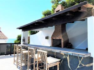 een patio met een bar met stoelen en een open haard bij Villa Cortés - 20 Minutes From Puerto Banús in Estepona