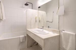 a white bathroom with a sink and a shower at Urban Hotel Estacao in Braga