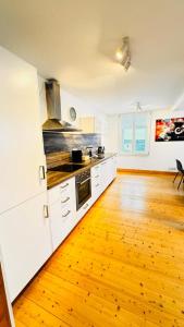 a kitchen with white cabinets and a wooden floor at Apartment II für 4 Aalen I Wlan I Netflix in Aalen