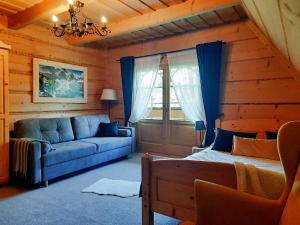 ein Wohnzimmer mit einem blauen Sofa und einem Bett in der Unterkunft Willa Płazówka Białczańska in Białka Tatrzańska