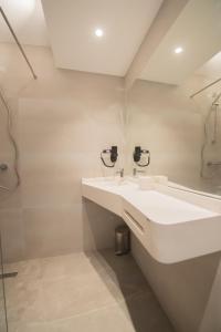 Hotel Atena*** في ساتورن: حمام أبيض مع حوض ومرآة