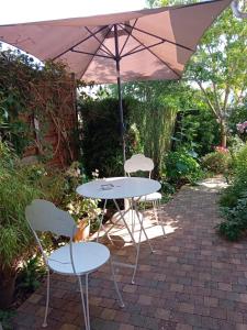 einen Tisch und Stühle unter einem Sonnenschirm auf einer Terrasse in der Unterkunft Chambre d hotes de charme in Vernon
