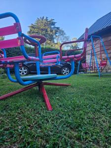 a group of colorful playground equipment on the grass at Cabañas Huinca Mapu - Sierra de los Padres in Sierra de los Padres +5 photos