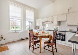 a kitchen with white cabinets and a table and chairs at The Lake House - Crimplesham Hall in Stradsett