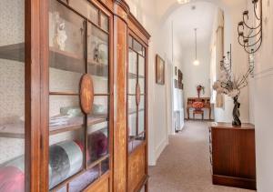 a hallway with a wooden cabinet with glass doors at The Lake House - Crimplesham Hall in Stradsett