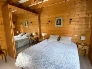 - une chambre avec un grand lit et un miroir dans l'établissement Gîte Autre Ruche, à Baudement