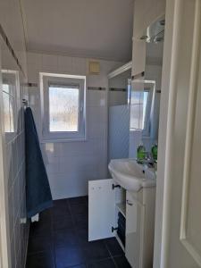 een witte badkamer met een wastafel en een spiegel bij Chalet in Lauwersoog