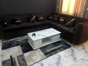 a living room with a black couch and a white coffee table at Cool meuble 2 in Ouagadougou