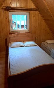 Cama en habitación de madera con ventana en Domek letniskowy w Kamionce en Kamionka