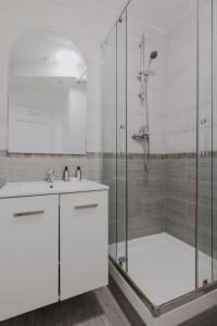 biała łazienka z prysznicem i umywalką w obiekcie CMG Batignolles - Lechapelais II w Paryżu