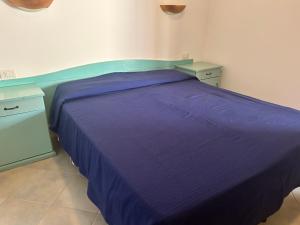 1 dormitorio con 1 cama de color púrpura y 2 mesitas de noche en Su Nuraghe, en SantʼAnna Arresi