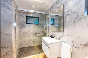 a white bathroom with a shower and a sink at The Milkwoods Luxury Living in Mossel Bay