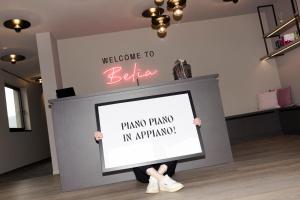 a person holding a sign in front of a wall at Belia Lofts - ADULTS ONLY - Apartments in Appiano sulla Strada del Vino