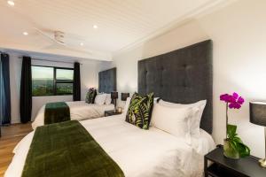 um quarto com 2 camas e uma grande cabeceira em The Milkwoods Luxury Living em Mossel Bay