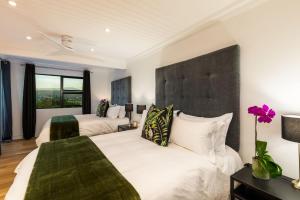 a bedroom with two beds and a large headboard at The Milkwoods Luxury Living in Mossel Bay
