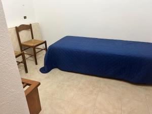a bedroom with a blue bed and a chair at Su Nuraghe in SantʼAnna Arresi