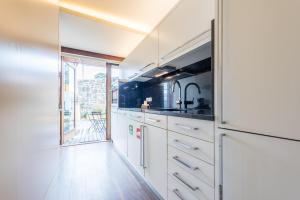 a kitchen with white cabinets and a large window at GuestReady - Flat59 Terrace in Porto