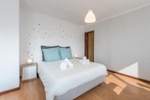 a bedroom with a large white bed with blue pillows at GuestReady - Porto Magic View in Vila Nova de Gaia