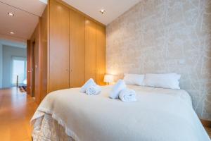 a bedroom with a large white bed with towels on it at GuestReady - Back To Climbwood in Monte Douro