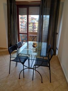 a glass table with four chairs and a dog on it at FERRARO ALLOGGIO TURISTICO in Ladispoli