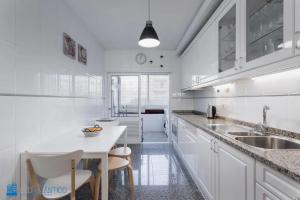 cocina blanca con fregadero y mesa en Gaia Beach & Pool Residence - Porto South Seashore, en Vila Nova de Gaia
