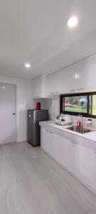 a white kitchen with a sink and a refrigerator at Casa Victoria Pension House-Makra in Somosomo