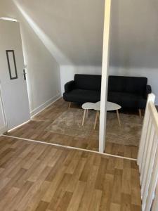 ein Wohnzimmer mit einem schwarzen Sofa und einem Tisch in der Unterkunft Duplex Huper in Amiens