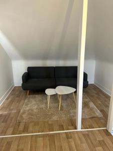 ein Wohnzimmer mit einem schwarzen Sofa und 2 Tischen in der Unterkunft Duplex Huper in Amiens
