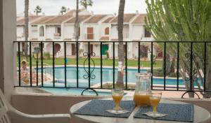 dos vasos de zumo de naranja en una mesa junto a una piscina en Apartamentos Aldeas De Taray Club, en La Manga del Mar Menor