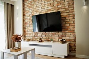sala de estar con TV en una pared de ladrillo en Apartament Bulwary 3, en Oświęcim