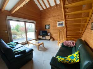 ein Wohnzimmer mit zwei Ledersofas in einer Hütte in der Unterkunft Gîte Autre Ruche in Baudement