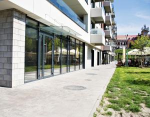 a building with large glass windows and a sidewalk at Magic Apartments - Bulwary 3 in Oświęcim