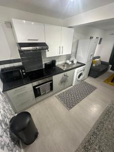 a kitchen with white cabinets and a stove top oven at Nice & Cozy Furnished 1 Bedroom Flat in Luton