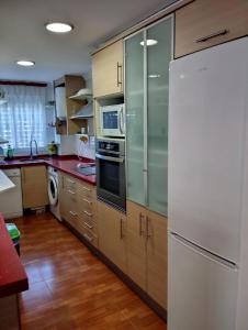 - une cuisine avec des placards en bois et un réfrigérateur blanc dans l'établissement Mikonos, à Gandía