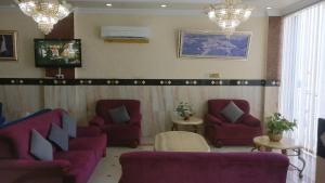 a waiting room with purple couches and chairs and chandeliers at فندق الخليج للشقق الفندقية GULF HOTEL APARTMENTS in Muscat