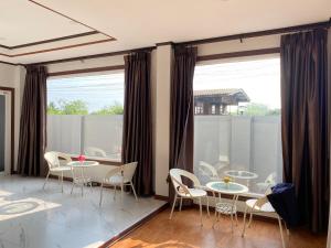 a dining room with tables and chairs and a large window at BanWongdee in Ban Pa Ton
