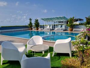 a pool with white chairs and a table and chairs at Avatara B condominium B54 in Ban Tha Fat