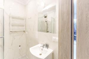 a white bathroom with a sink and a shower at Nadmorski Apartament V by Holiday&Sun in Grzybowo