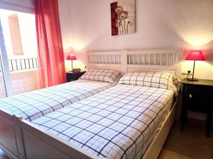 a bedroom with a bed and two lamps and a window at Espliego Pool View Apartment in Torre-Pacheco